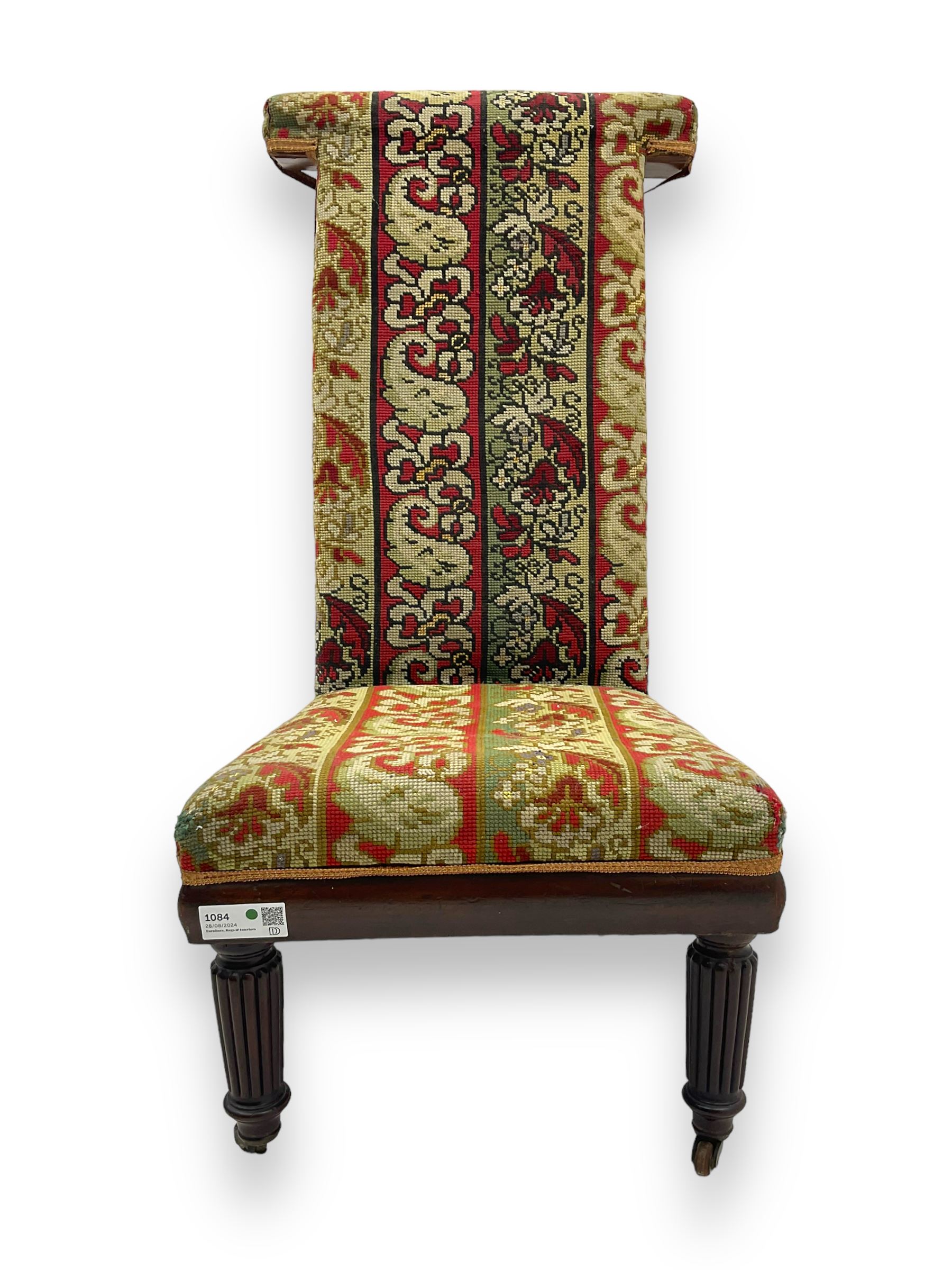 19th century mahogany framed prie-dieu chair, upholstered in red and green patterned fabric, high back with rolled top, standing on turned front supports with castors