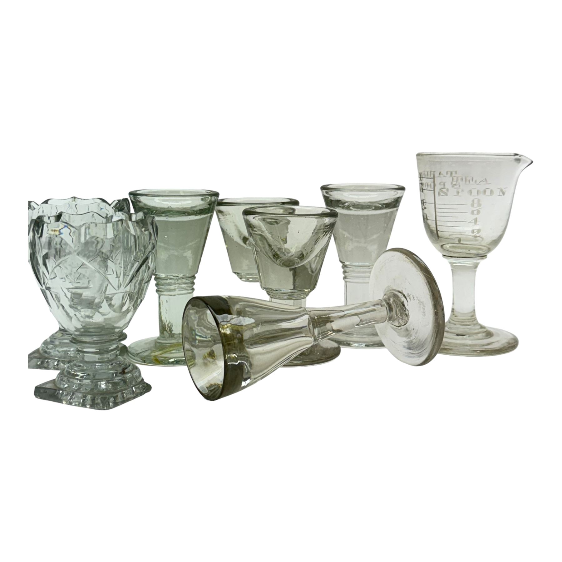 Five 19th century penny lick glasses, together with a pair of 19th century cut glass open salts with lemon squeezer bases, and a 19th century glass measure, largest example H12cm
