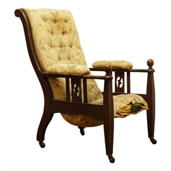  Arts & Crafts oak armchair, upholstered back, seat and arm pads, pierced and railed side panels, the square tapering supports with ball finials, brass sockets and ceramic castors  
