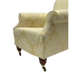 Traditionally shaped hardwood-framed armchair, rolled back and arms, upholstered in pale gold and cream damask fabric with repeating foliate pattern, on turned feet with brass cups and castors