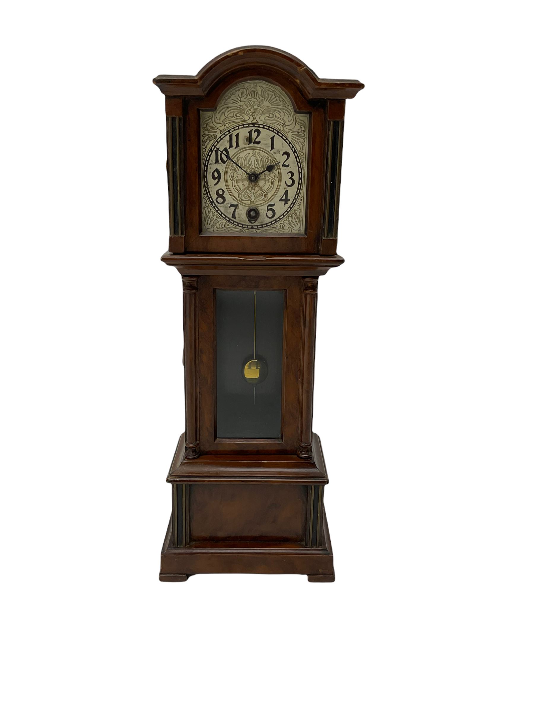 A miniature spring driven longcase clock made in Germany by the Hamburg American Clock Company c 1890, with a mahogany finished case, break arch pediment and opening hood door, case with a fully glazed opening trunk door on a short plinth with raised feet, with an etched silver effect dial, Arabic numerals, minute track and spade hands, 8-day key wound movement with a silk suspension and visible pendulum.




