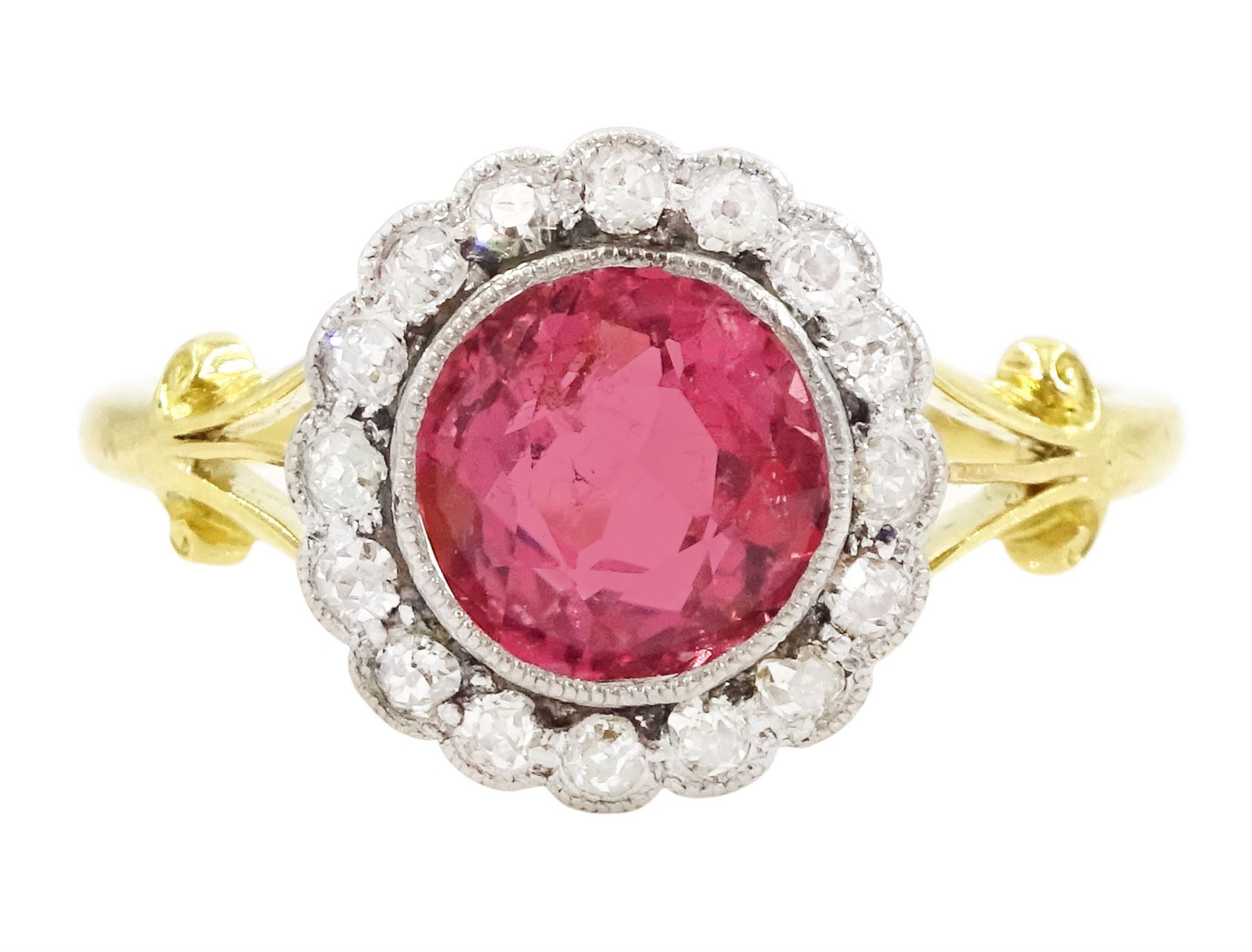 Early 20th century gold tourmaline and diamond cluster ring, milgrain set single stone pink tourmaline of approx 1.35 carat, surrounded by sixteen old cut diamonds, to a split design scroll shank, stamped 18ct, total diamond weight approx 0.30 carat