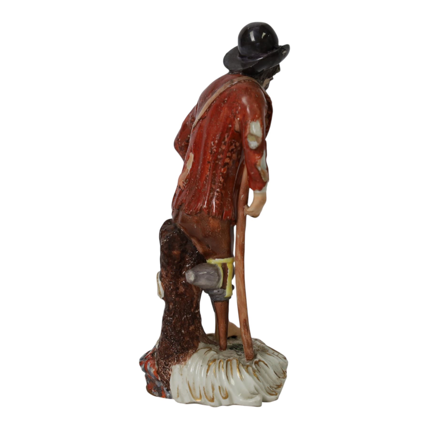 Mid 18th century Furstenberg figure, modelled as a beggar or mendicant with peg leg and bare foot, circa 1755, modelled by Simon Feilner, wearing tattered clothes, one arm supporting an alms pouch, the other holding a crutch, upon a part scrolled base, bearing paper labels beneath including one inscribed 'Sammlung Wilhelm Gumprecht 322', H15cm