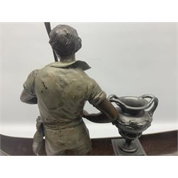 Bronzed and pewter figure group depicting a gentleman stood holding an oar behind his long boat beside a twin handled urn, raised on ornate base with whimsical grotesque fish supports, H52cm