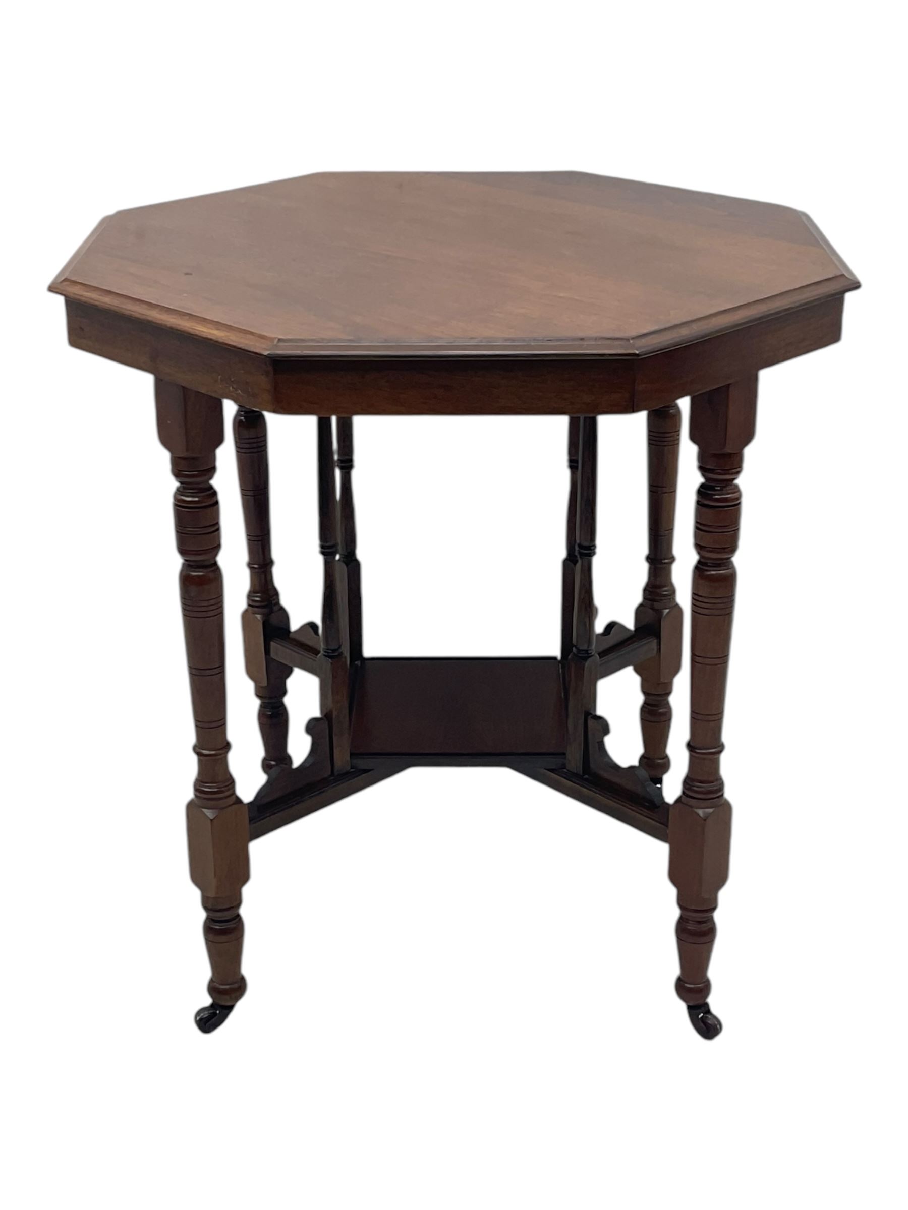 Victorian oak occasional table, octagonal top with bevelled edges, lower section fitted with a square undertier united by decorative shaped stretchers, on turned supports with castors