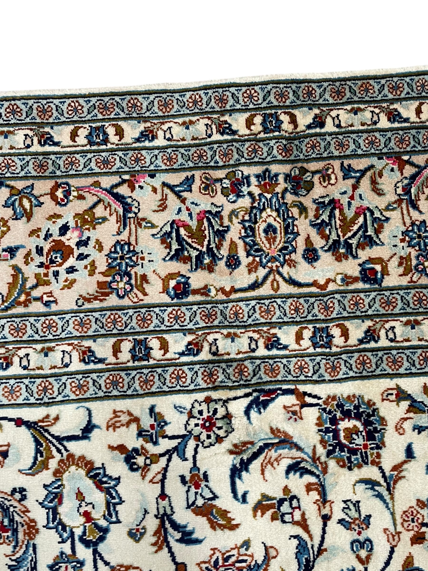 Persian Kashan ivory ground rug, decorated with curled leafy branches and palmettes, the border with scrolling design decorated with further palmettes, within floral pattern guard stripes