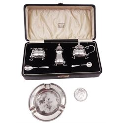 1930s silver three piece cruet set, comprising open salt, mustard pot with cover and pepper, and two cruet spoons, each upon four pad feet, hallmarked Adie Brothers Ltd, Birmingham 1939, in tooled leather box with silk and velvet lined interior, together with a mid 20th century silver ashtray, hallmarked Walker & Hall, Sheffield 1945 and George IV 1821 silver crown coin 