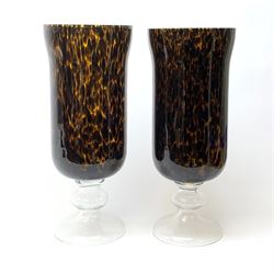 Two large glass hurricane lamps, with tortoiseshell effect bodies, clear knopped stems and spreading feet, largest H55cm. 