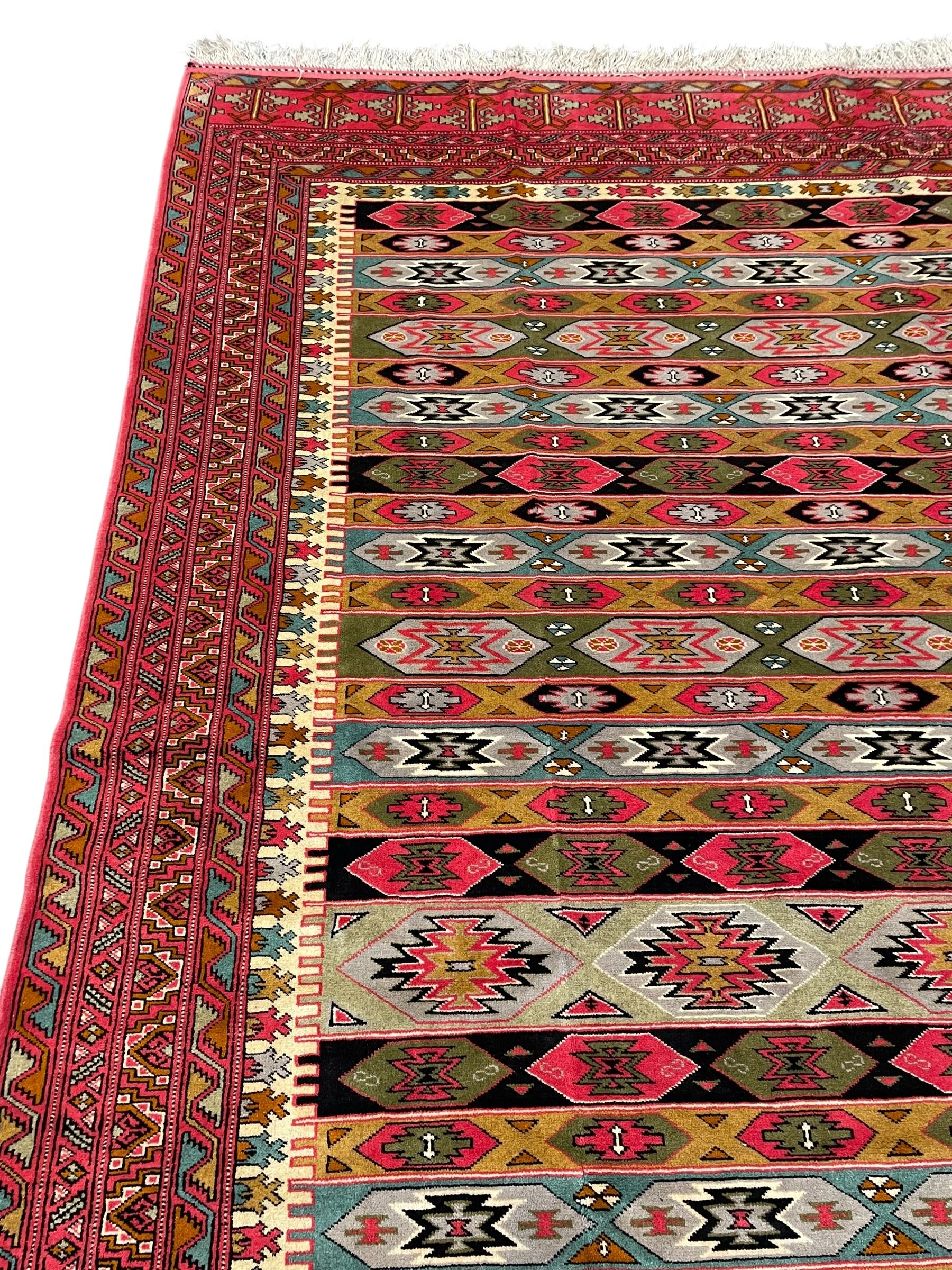 Persian red ground rug, the field divided into horizontal rows and decorated with geometric motifs, intricately pattern borders and end panels