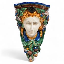 Pair of early 20th century Majolica wall brackets or corbels, formed as two ladies in high relief surrounded by fruit and foliage, on a blue and green ground H30cm 