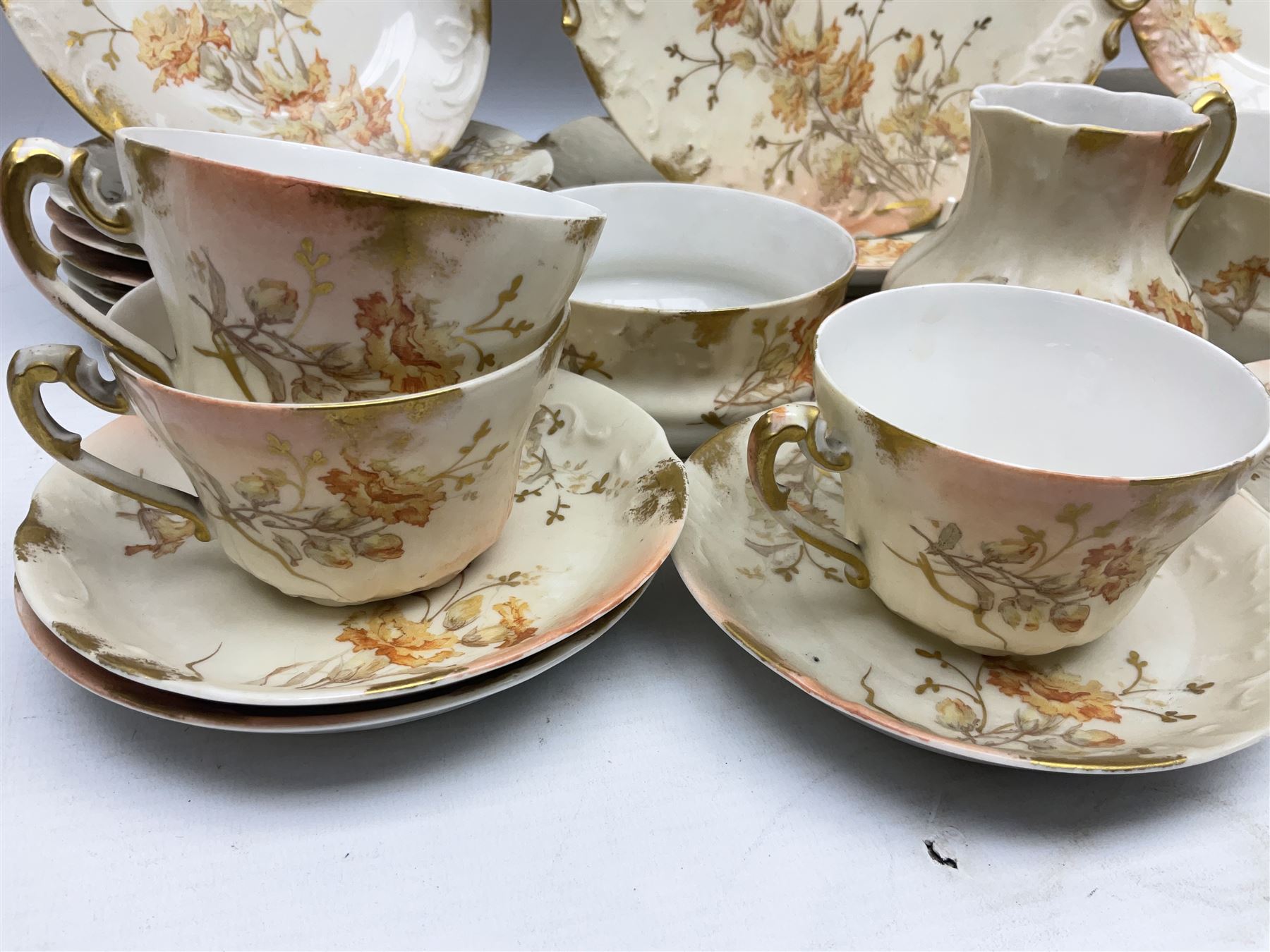 Early 20th century Limoges part tea service, decorated with floral sprays and gilt on merging peach and white ground, comprising six teacups, twelve side plates, six smaller plates, milk jug, open sucrier, slop bowl and two cake plates, many marked R Delinieres Limoges D&C France to base