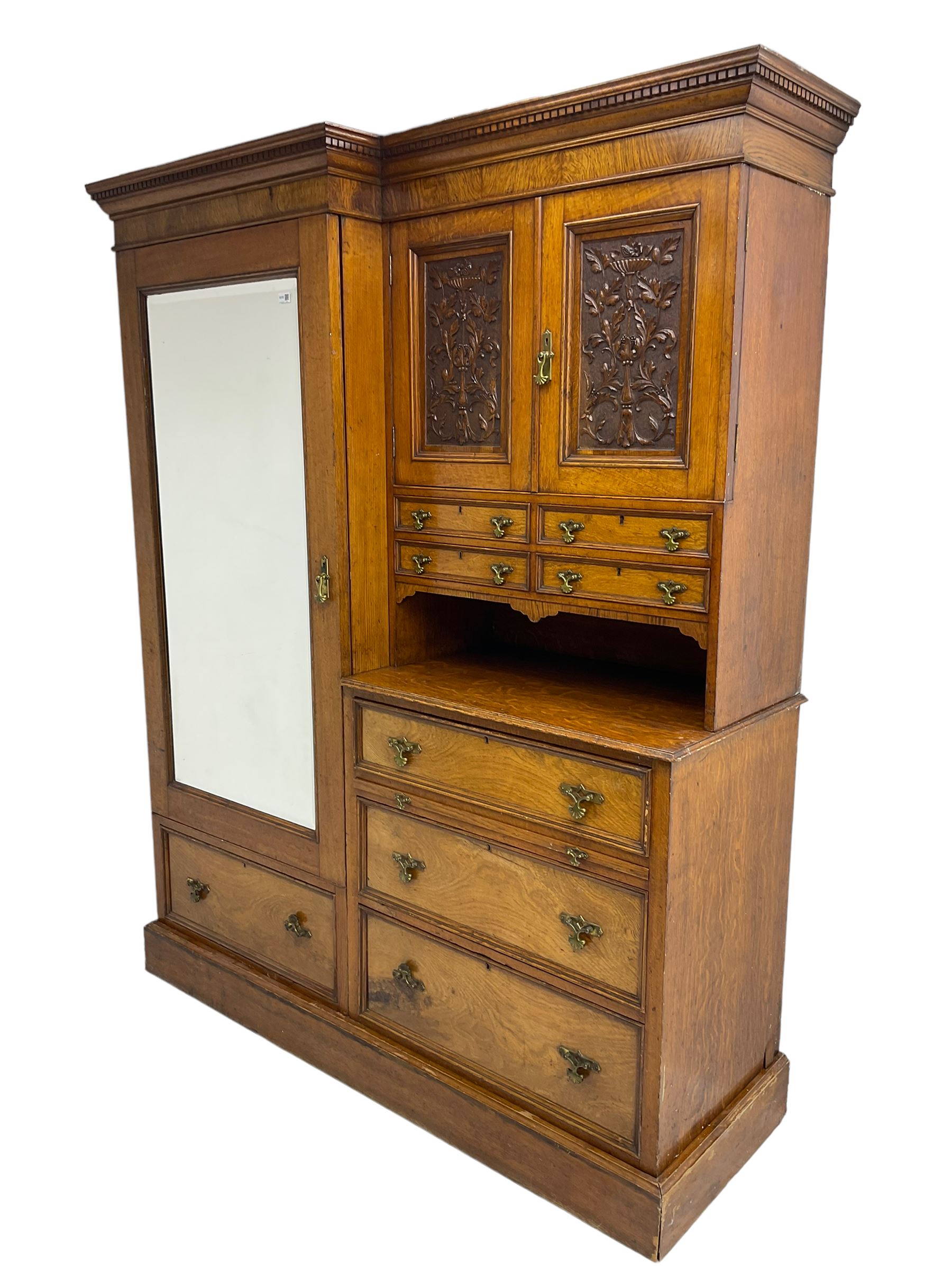 Victorian figured oak and pollard oak combination wardrobe, projecting dentil cornice, the left hand side enclosed by large bevelled mirror glazed door over drawer, the interior with sliding hanging rail, the right hand side with cupboard enclosed by two panelled doors relief carved with urn and trailed trailing foliage, four small drawers over shelf, three drawers and brushing slide, the slide with tooled and gilt blue leather inset, plinth base