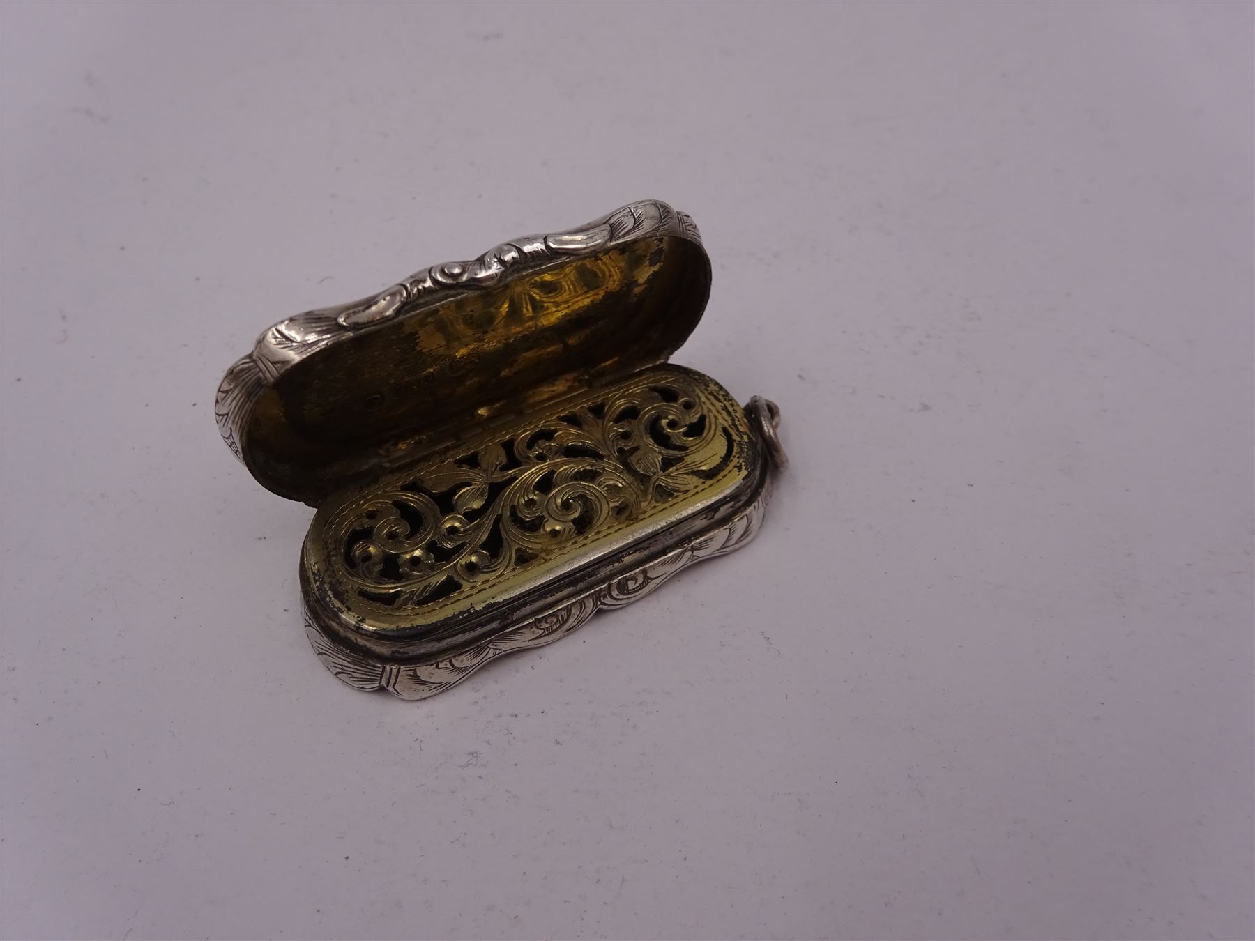 Victorian silver vinaigrette, of oval form with shaped rim, with engraved scrolling and foliate decoration and cartouche with initials, with foliate pierced gilt interior, hallmarked David Pettifer, Birmingham 1855, L4.3cm