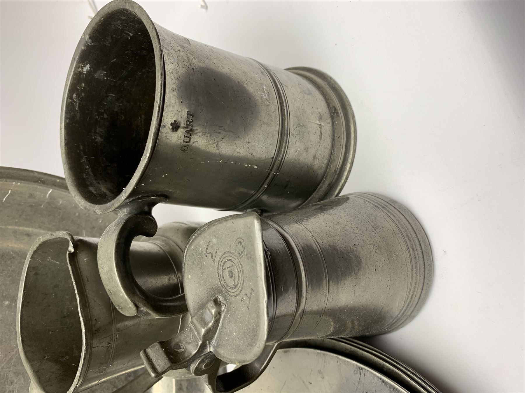 Collection of 18th and 19th century pewter, comprising two chargers, eight large plates, twenty six smaller plates, two bowls, three lidded measures, two jugs, tappit hen, and tankard, the plates with various marks and touch marks, including pseudo 'hallmarks', largest charger 37cm, large plates D30cm, smaller plates D24.5cm, tappit hen H26.5cm