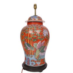 Table lamp of baluster form, decorated with ducks and lilies upon a red ground upon a circular wooden base, H64cm