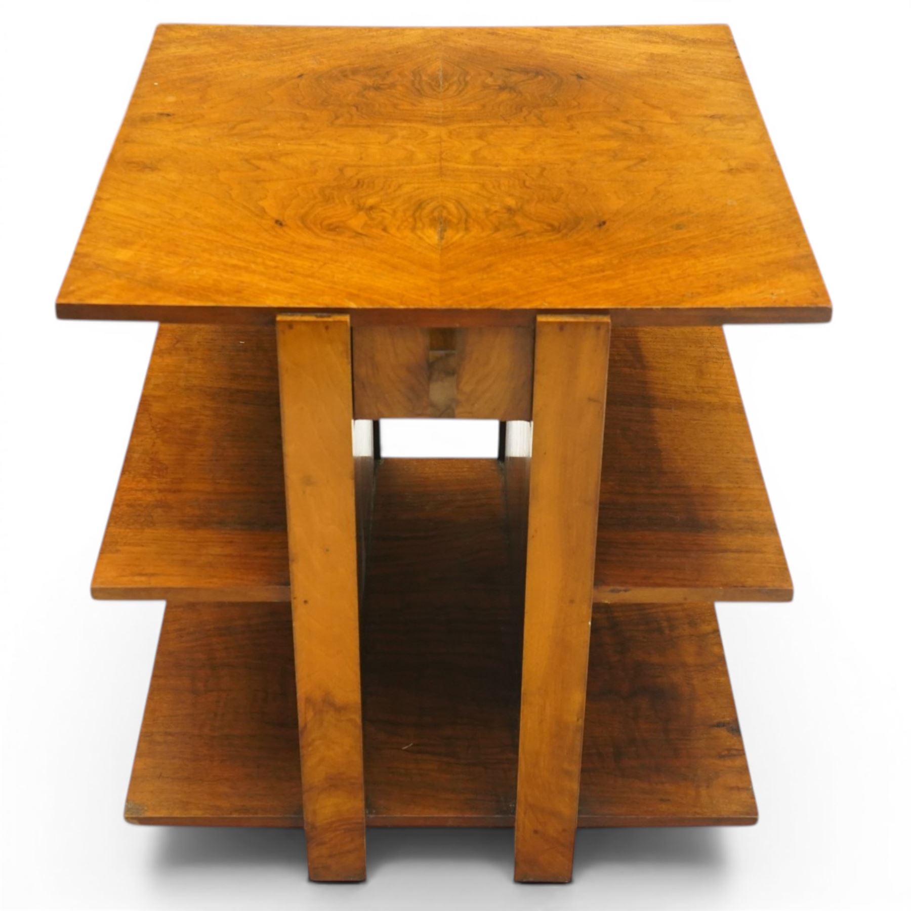 Art Deco walnut coffee table, square book-matched veneered top over single frieze drawer with brass handle, flanked by open side shelves, raised on rectangular end supports