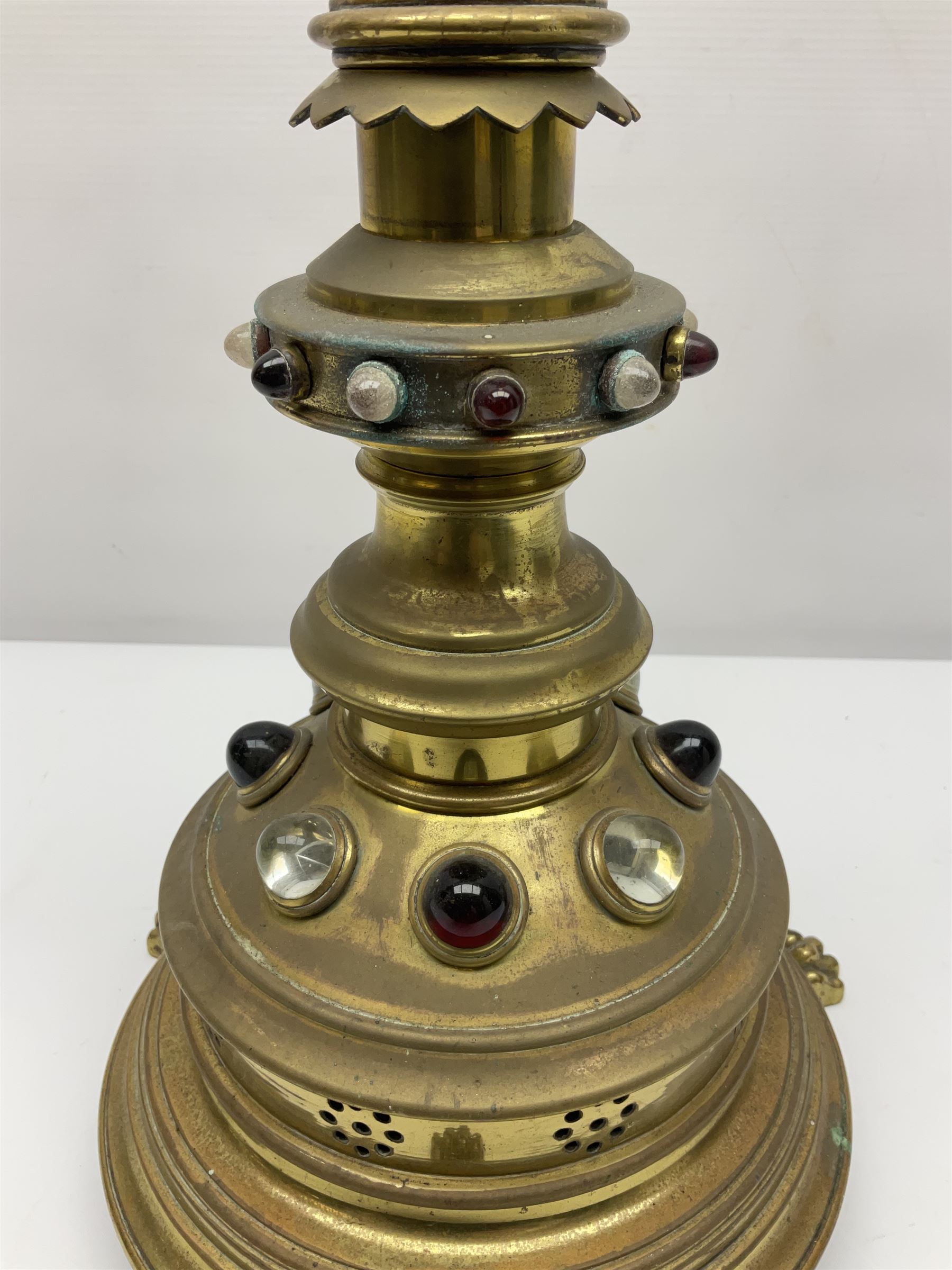 Brass alter cross, decorated with glass cabochons, upon a acicular stepped base and three claw feet, H73cm 