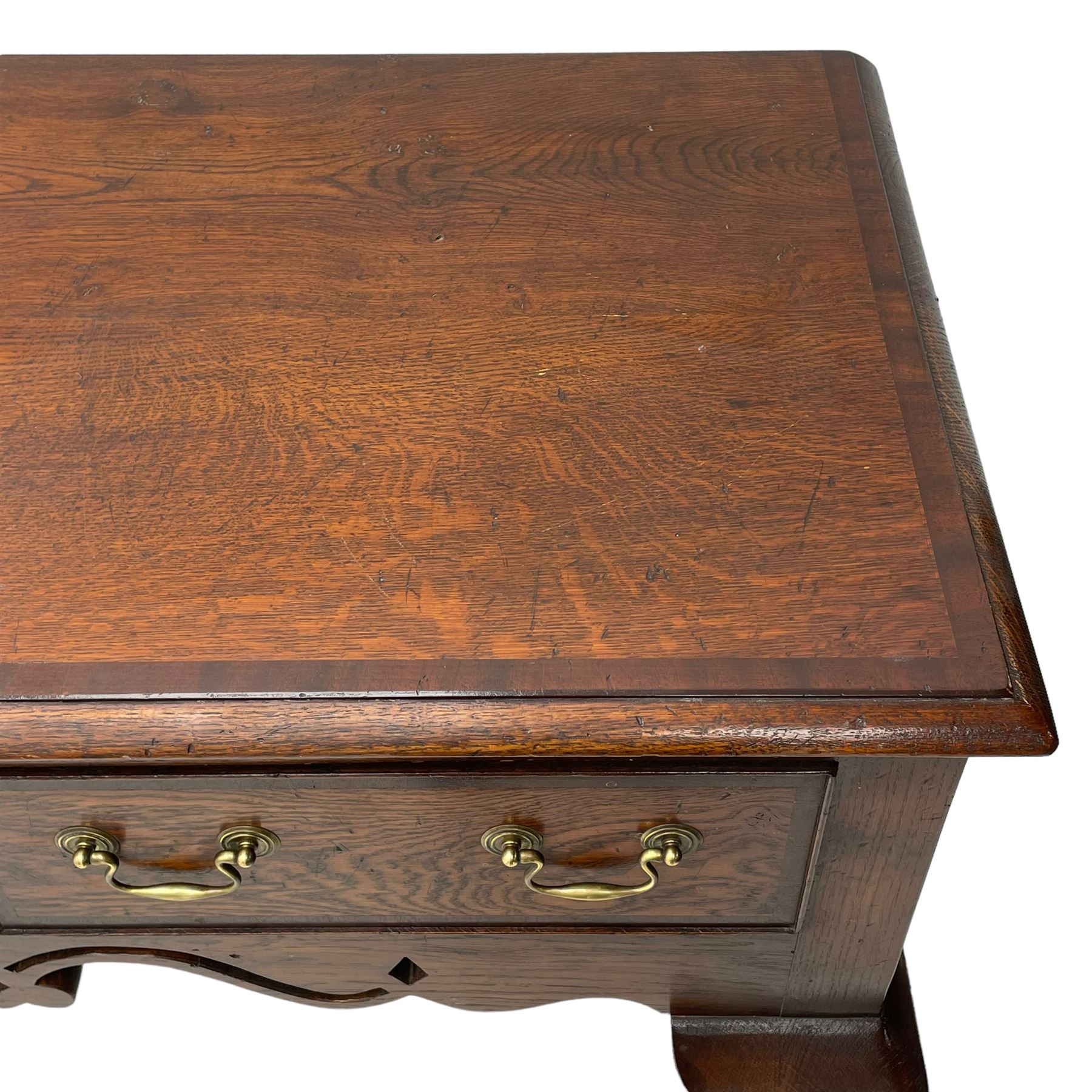 Georgian design oak and mahogany dresser base, the rectangular moulded top with mahogany band, three cocked-beaded and banded drawers over shaped a pierced apron, circular brass handle plates and swan neck handles, on C-scroll carved cabriole supports 