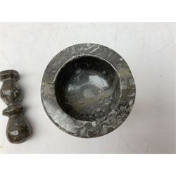 Polished stone pestle and mortar with multiple fossil specimens, including an ammonites and orthoceras, 