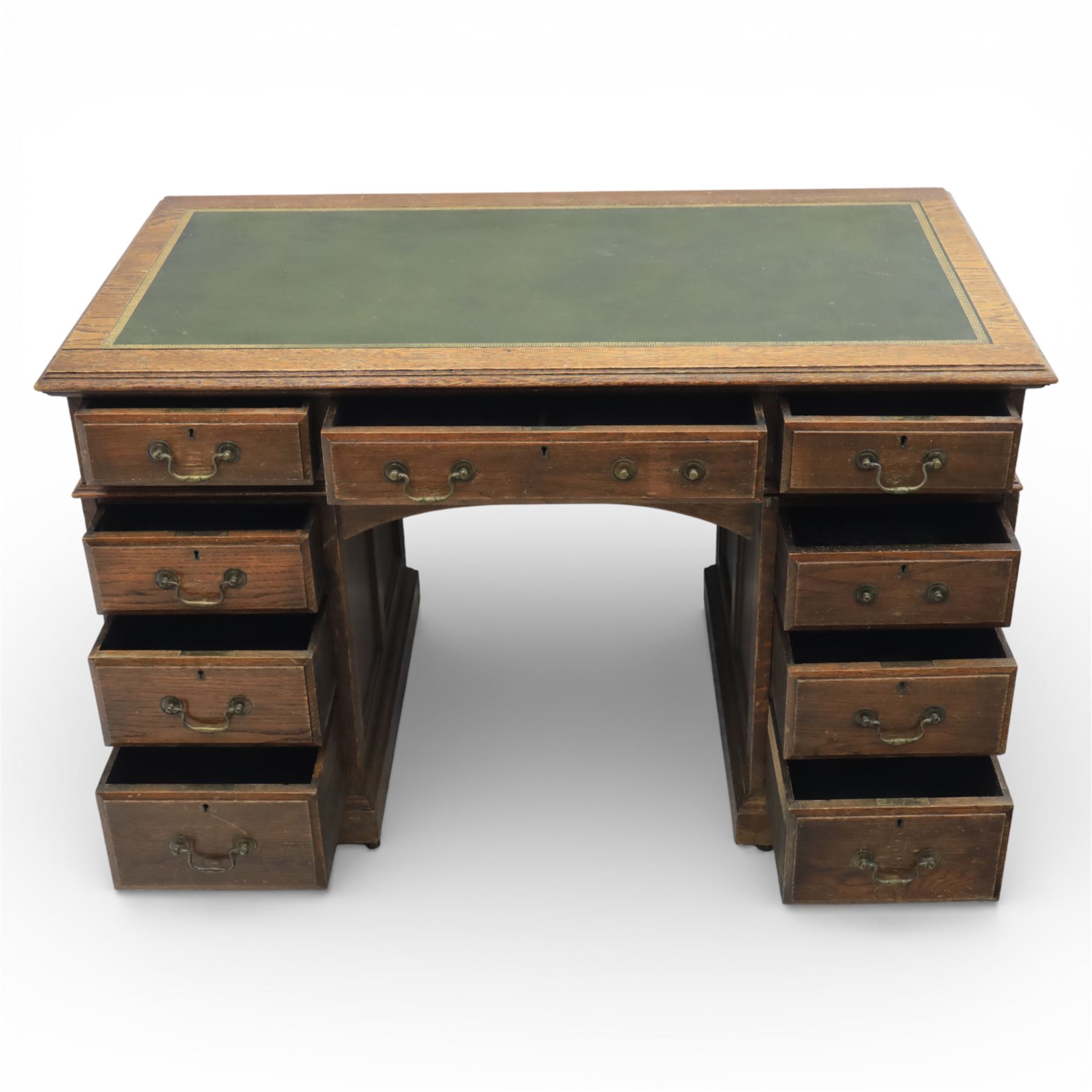 Victorian oak pedestal desk, the rectangular top with inset green leather writing panel and decorative gilt border, over a central frieze drawer flanked by two short drawers, twin pedestals each fitted with four drawers with brass handles, arched kneehole opening, standing on moulded plinth bases