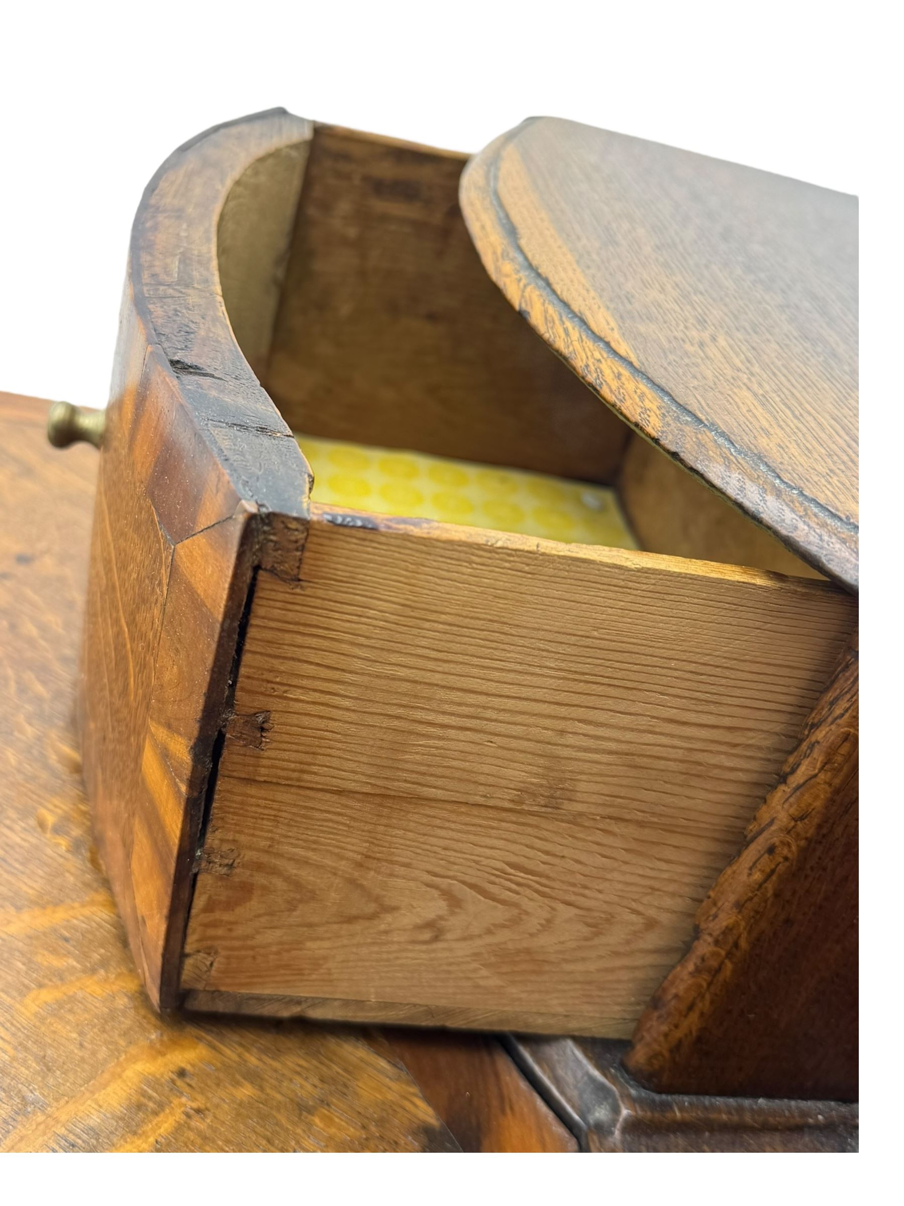 Late 19th century continental oak commode, serpentine fronted with parquetry and crossbanded decoration, the raised superstructure back fitted with a central bank of five recessed drawers flanked by concave drawers, above three full-width drawers with brass ring handles, raised on cabriole supports