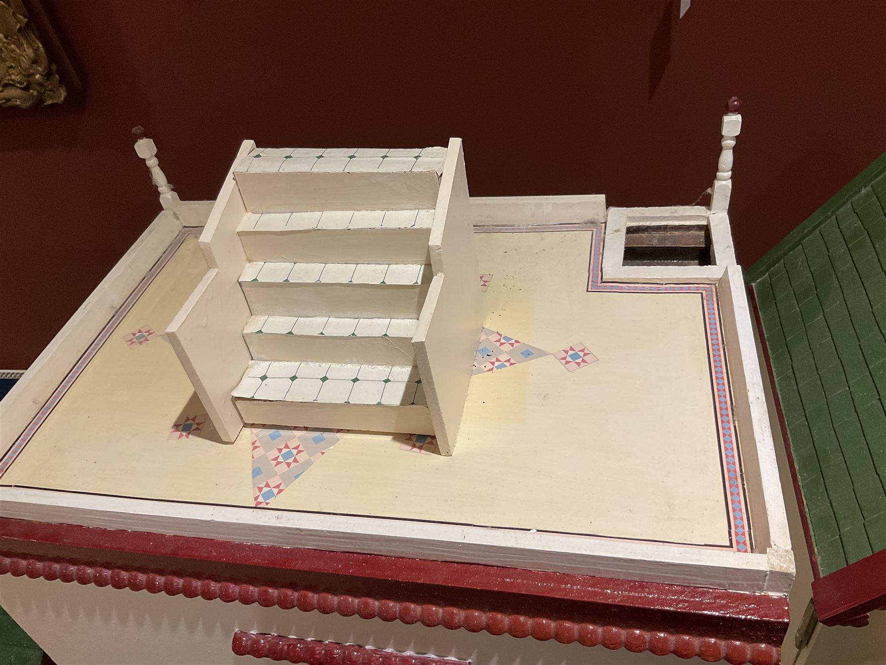 Seagull Pub - scratch-built wooden doll's house as a two-storey gable fronted public house painted in white green and maroon; the hinged front with ground floor veranda and window over opening to reveal two fully furnished rooms with dog-leg staircase and well stocked bar with bar-tender L31cm H62cm D37cm; together with Corner Shop and Dollies Pantry; a similarly painted scratch-built wooden two-storey flat-roofed doll's house as a well stocked ground floor grocery shop with stairs up to two further fully furnished rooms and more stairs giving access to a roof terrace L46cm H57cm D33cm (2)