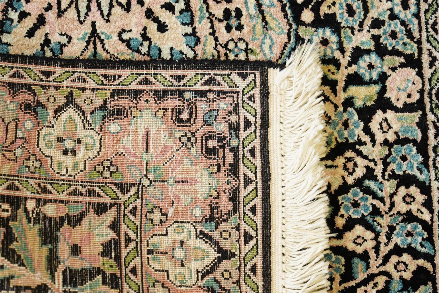 Persian style rug, central floral medallion surrounded by intricate palmetters, vines and rosettes, navy blue ground with ivory and pink highlights