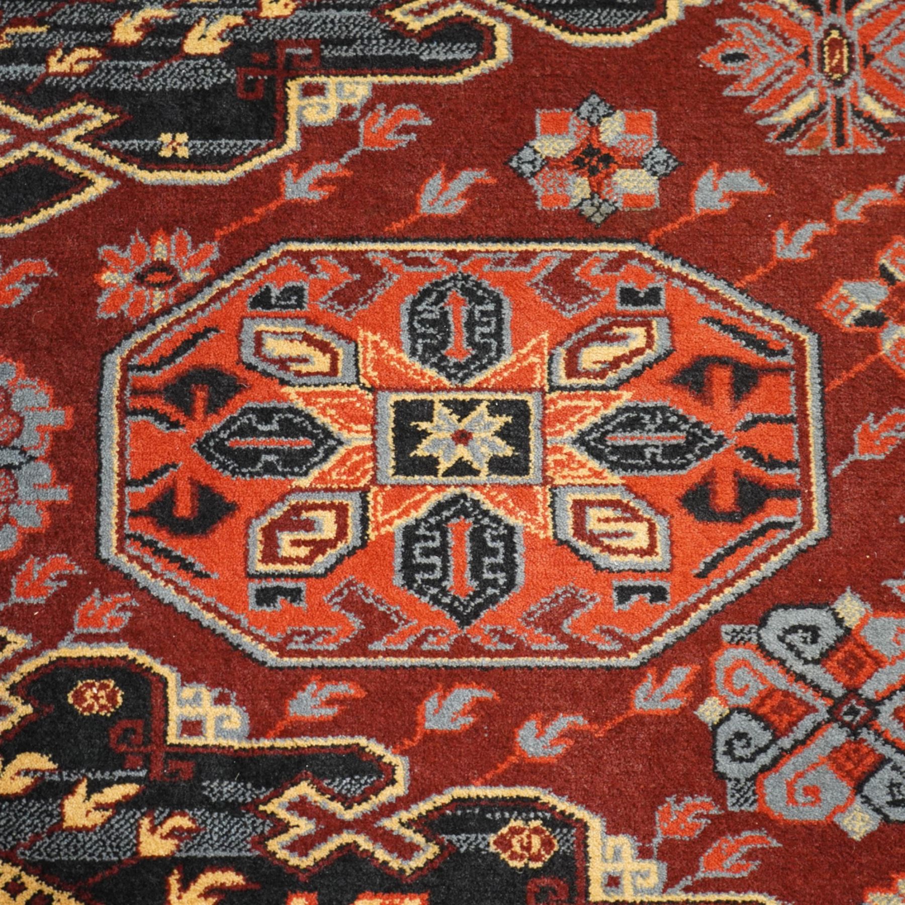 Persian Karabagh design rug, red madder field with three linked octagonal medallions surrounded by floral geometric motifs within multiple stylized borders 