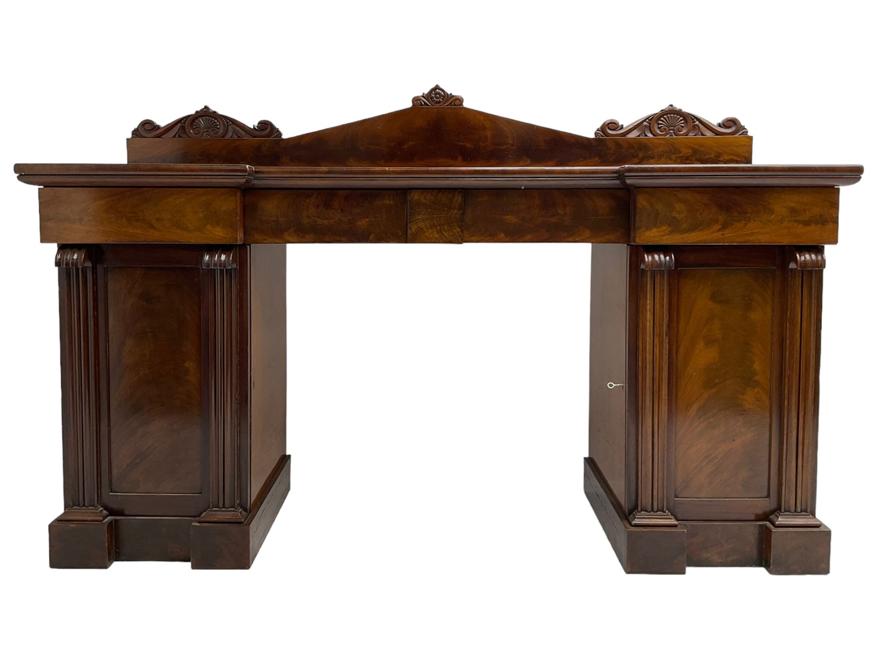 Early 19th century mahogany reverse break-front twin pedestal sideboard, raised back carved with cartouche and rosette detail with extending scrolling, fitted with two frieze drawers, the flanking panelled cupboards enclosing sliding trays and cellarette drawer