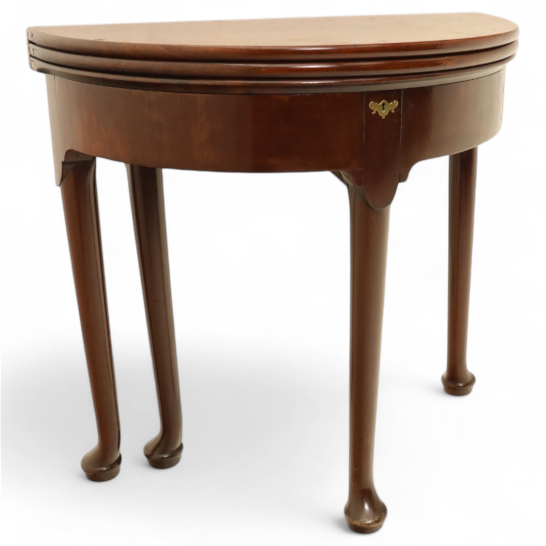 20th-century Georgian Revival style double fold-over card table, the first hinged circular top with polished mahogany surface above a second hinged circular top revealing a green baize playing surface with four counter-wells, underneath with a recessed compartment with and  chip and dice wells, the apron with fitted lock and key, raised on slender straight legs with pad feet 