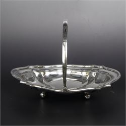 Early 20th century silver swing handled basket, of oval form with shaped rim and upon four bun feet, hallmarked C W Fletcher & Son Ltd, London 1918