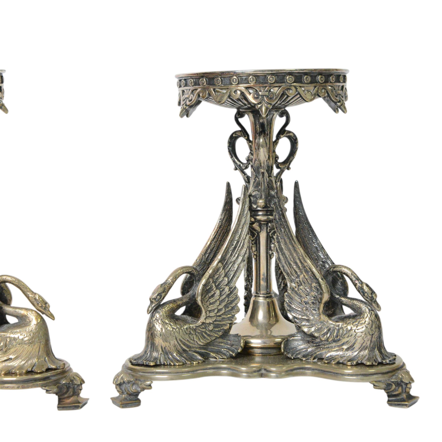Pair of late 19th century silver plated tazza or centre piece stands, each of trefoil form upon acanthus mounted square pad feet, rising to a central decorative stem flanked by three stylised swans, the open foliate scrolling upper section supporting a circular plate stand, H19cm