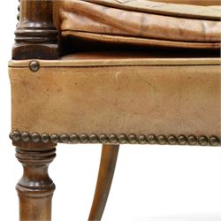 Early 20th century Georgian design mahogany framed desk or club armchair of tub form, with turned pilaster arm supports and legs with rear splayed supports, upholstered in faded tanned leather with loose seat cushion