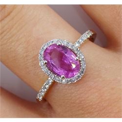 18ct gold oval pink sapphire and diamond halo cluster ring, with diamond set shoulders, stamped 750, sapphire approx 1.40 carat