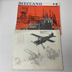 Meccano - quantity of loose sections in black, silver and yellow including various size flat and flanged plates, pulley and gear wheels and tyres, various size perforated strips, rods, spanners and crank handles, brackets, double angle and curved strips, various set instruction manuals etc; in wooden tray