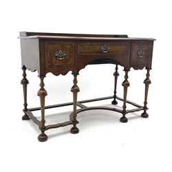 20th century Queen Anne style kneehole writing table, the figured and moulded rectangular top with raised gallery back, shaped front apron fitted with three drawers, on turned supports joined by a series of shaped and curved stretchers, on turned bun feet, the central drawer set with circular ivorine label inscribed ‘Pallmall, Hamptons, London’