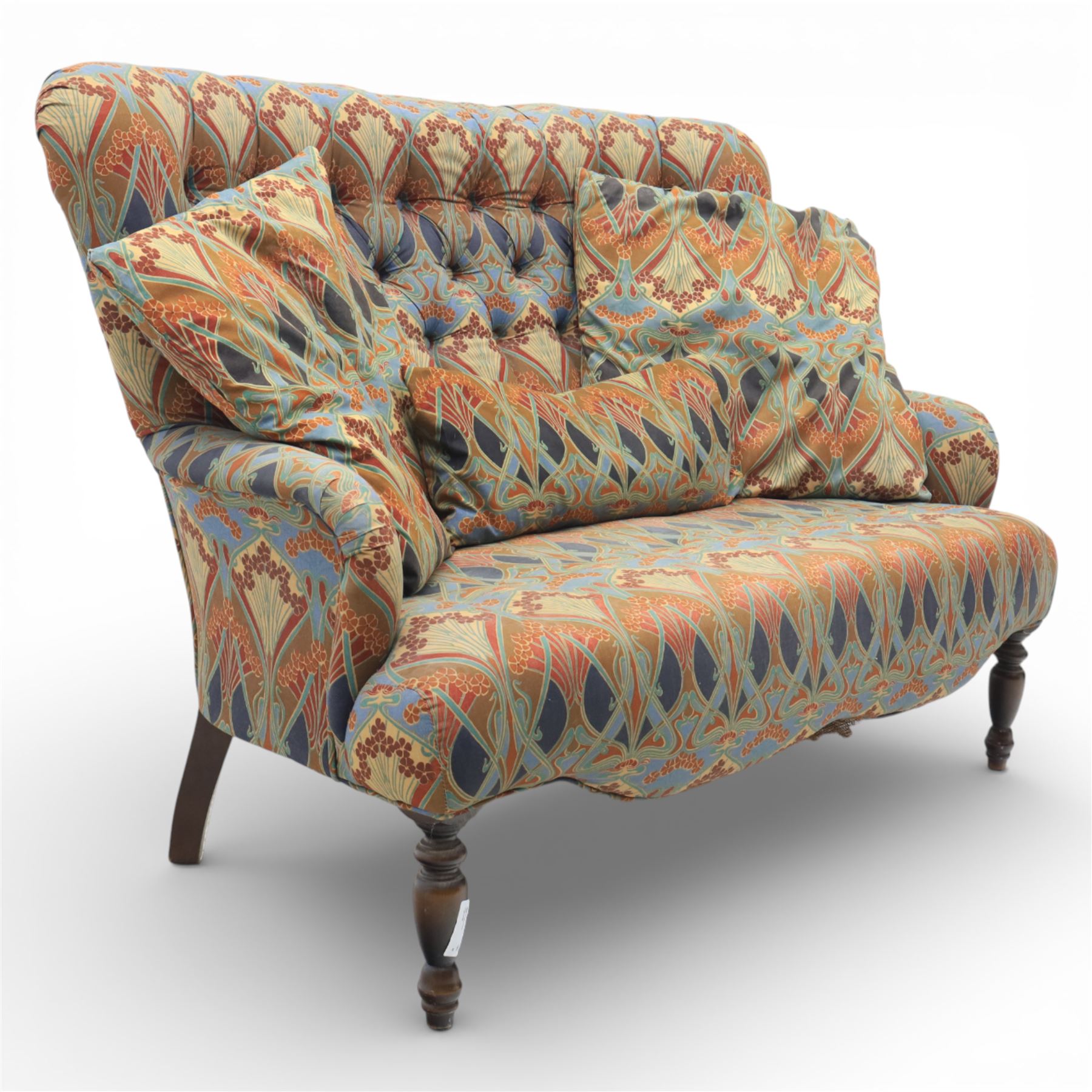 Late 20th century Liberty upholstered two seater sofa, the shaped back and arms with deep buttoned upholstery, covered in Art Nouveau fabric with stylised floral and foliate motifs, loose scatter cushions en suite, raised upon turned tapering front supports and swept rear legs
