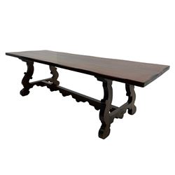 Large hardwood dining table, on shaped open ends supports joined by stretcher 
