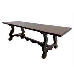 Large Spanish hardwood dining table, on shaped open ends supports joined by stretcher 
