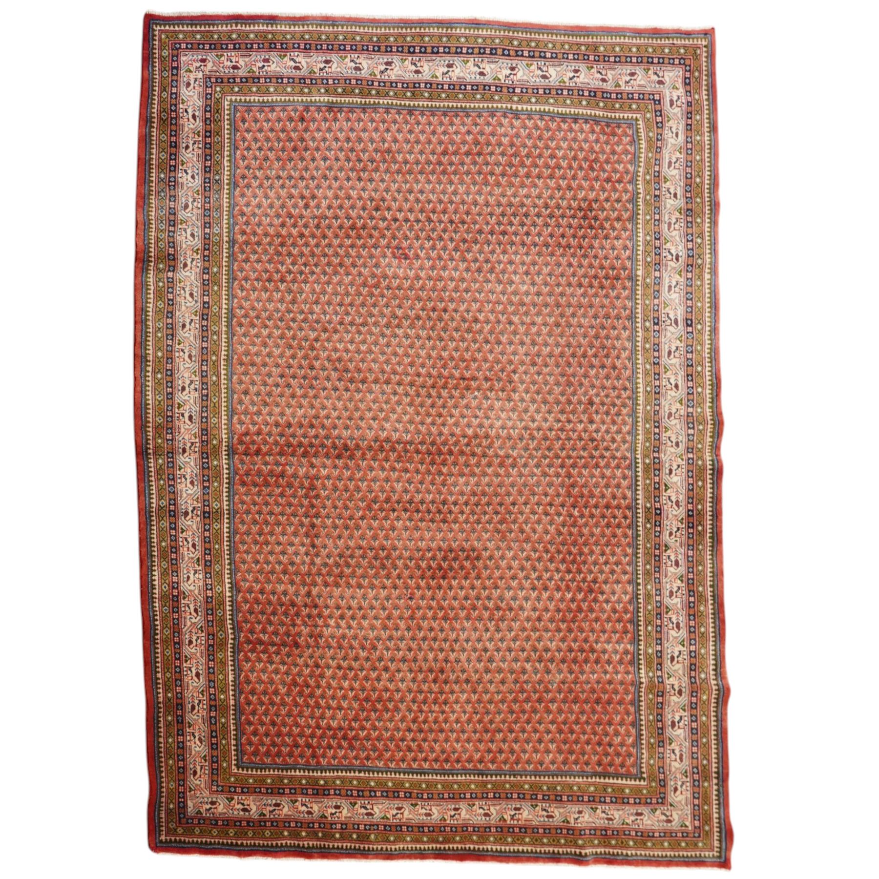 West Persian Boteh-Mir hand-knotted rug, madder red field densely decorated with a repeating lattice of of small boteh motifs arranged in diagonal rows enclosed by a broad border of stylized geometric devices and angular floral ornament between multiple guard stripes with cotton fringe ends