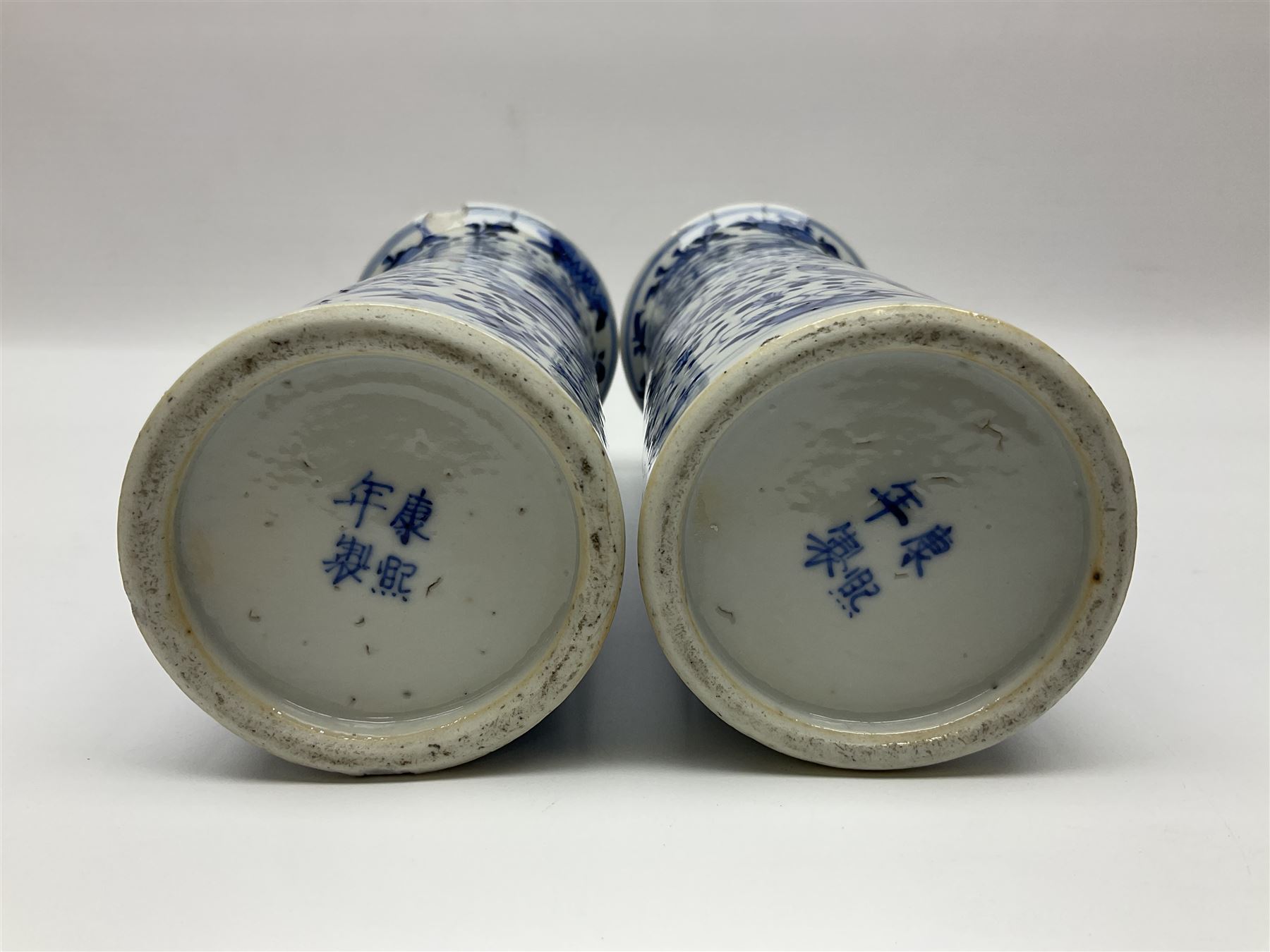 Pair of Chinese blue and white cylindrical vases, decorated with bird and flowers surrounding central figures holding a large vase, H20cm