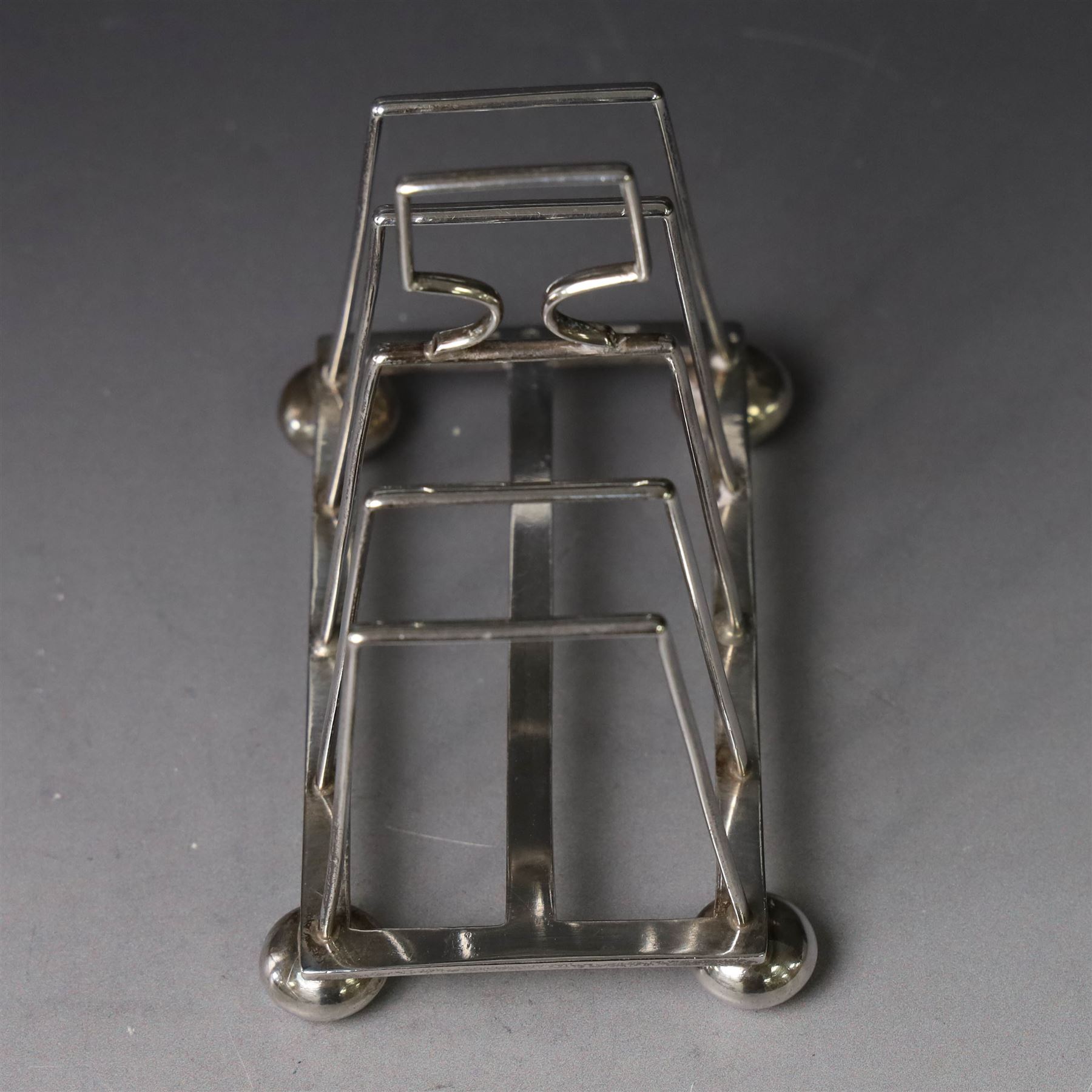 Victorian silver toast rack, with five angular bars and loop handle, upon four squat bun feet, hallmarked Thomas Hayes, Birmingham 1893, height including handle H10cm