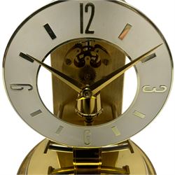 A  late 20th century German Kieninger & Obergfell, “Kundo” battery operated 
mantle clock under an acrylic shade, with an electrically operated solenoid pendulum housed on a 16cm circular brass base with three adjustable feet, skeleton movement with a visible escapement through an 4-1/2” open chapter ring dial, with gilt baton hands, three-hour numerals and baton markers.  H30cm 




