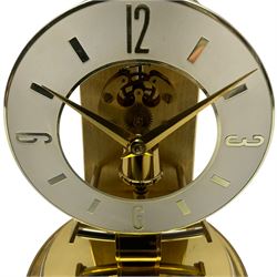 A  late 20th century German Kieninger & Obergfell, “Kundo” battery operated 
mantle clock under an acrylic shade, with an electrically operated solenoid pendulum housed on a 16cm circular brass base with three adjustable feet, skeleton movement with a visible escapement through an 4-1/2” open chapter ring dial, with gilt baton hands, three-hour numerals and baton markers.  H30cm 




