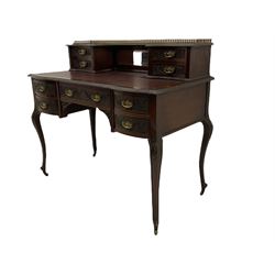 Late Victorian walnut writing desk, raised drawers with central bevelled mirror with raised gilt metal gallery, shaped moulded top with leather inset, fitted with five drawers, raised on cartouche carved cabriole supports with brass castors, the drawer fronts relief carved with scrolled foliage 