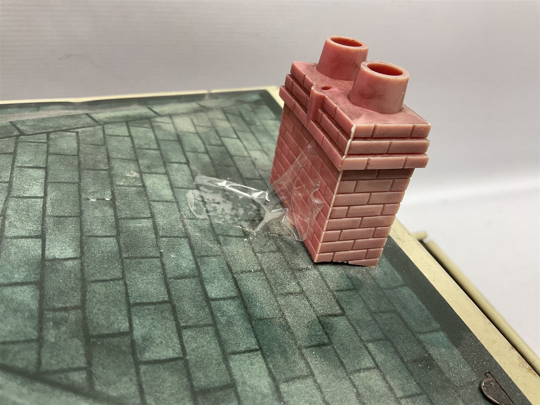 Mid-20th century Mettoy tin-plate double-fronted two-storey doll's house, the front elevation with five unglazed windows flanked by green shutters, central opening door, open back giving access to five rooms together with an attached garage, 60cm wide