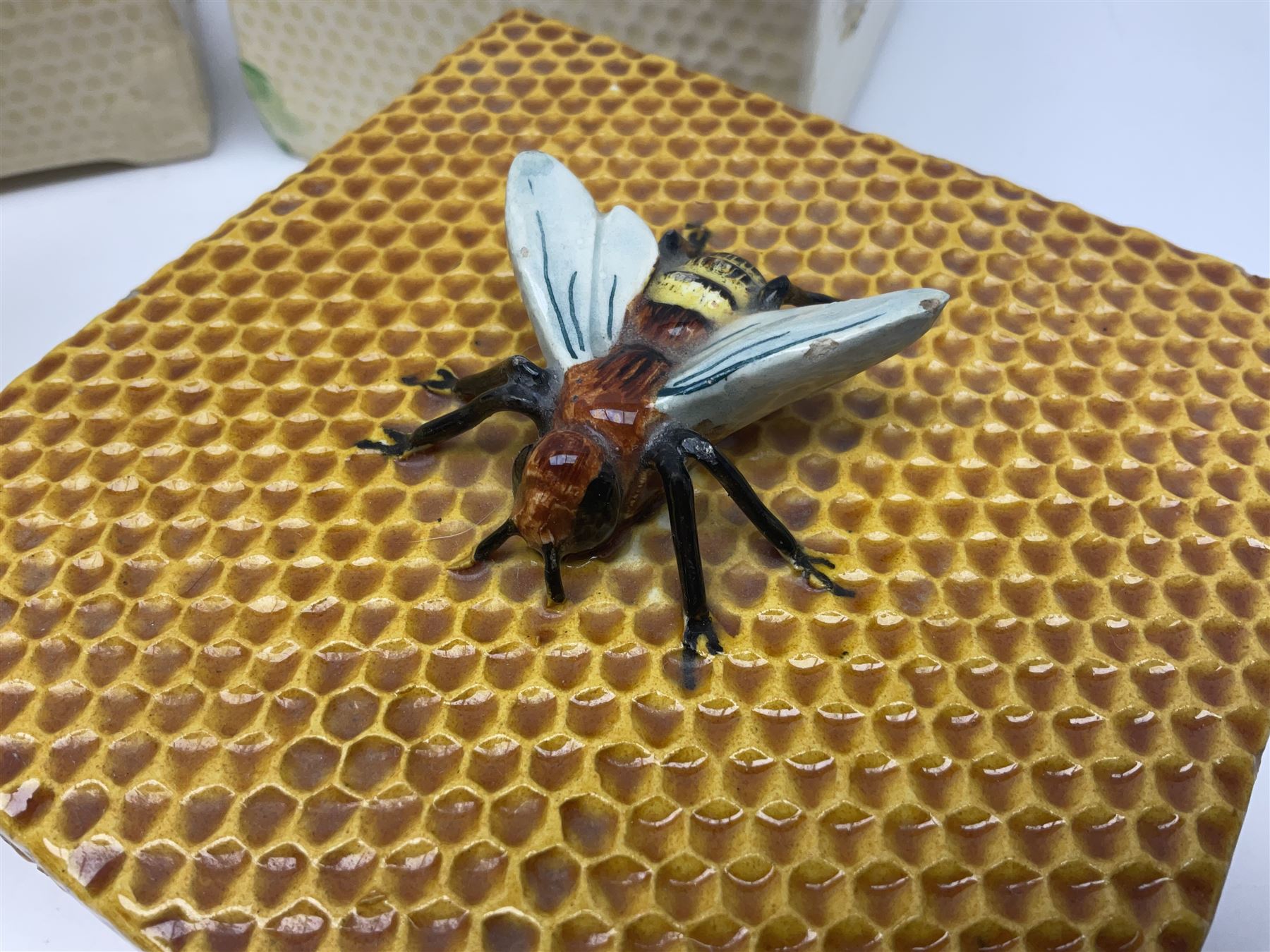 Four square honey boxes with lids,  each decorated with honeycomb pattern and finished with a bee finial