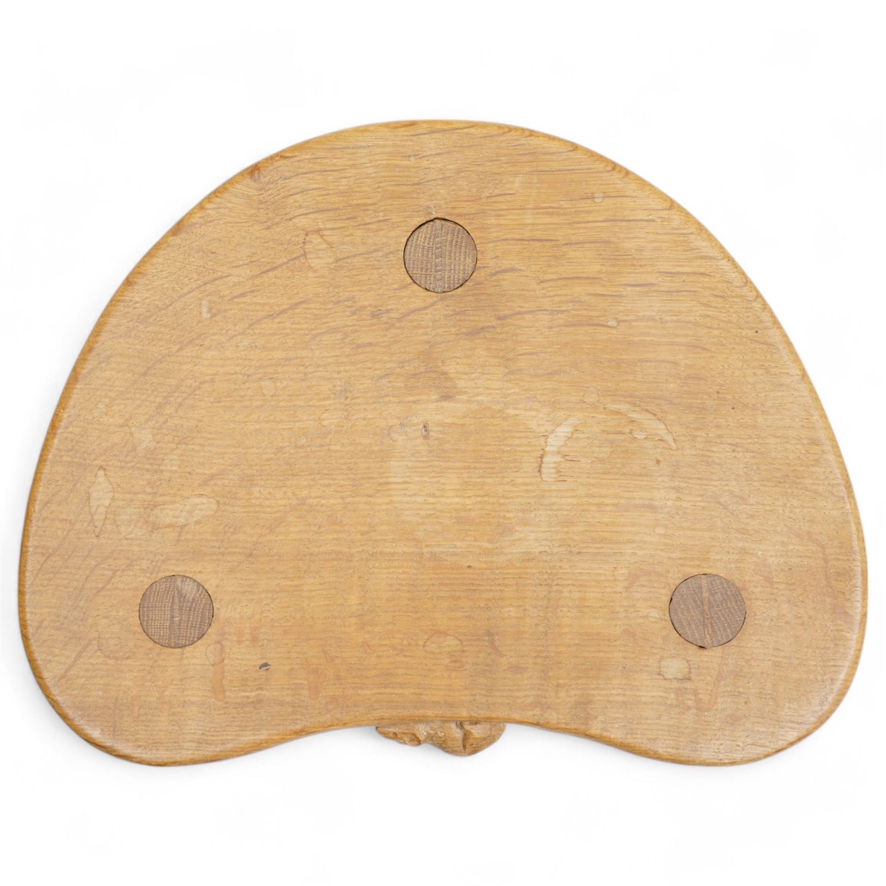 Mouseman - oak three-legged milking stool, dished kidney-shaped seat carved with mouse signature, on three octagonal tapered supports, by the workshop of Robert Thompson, Kilburn