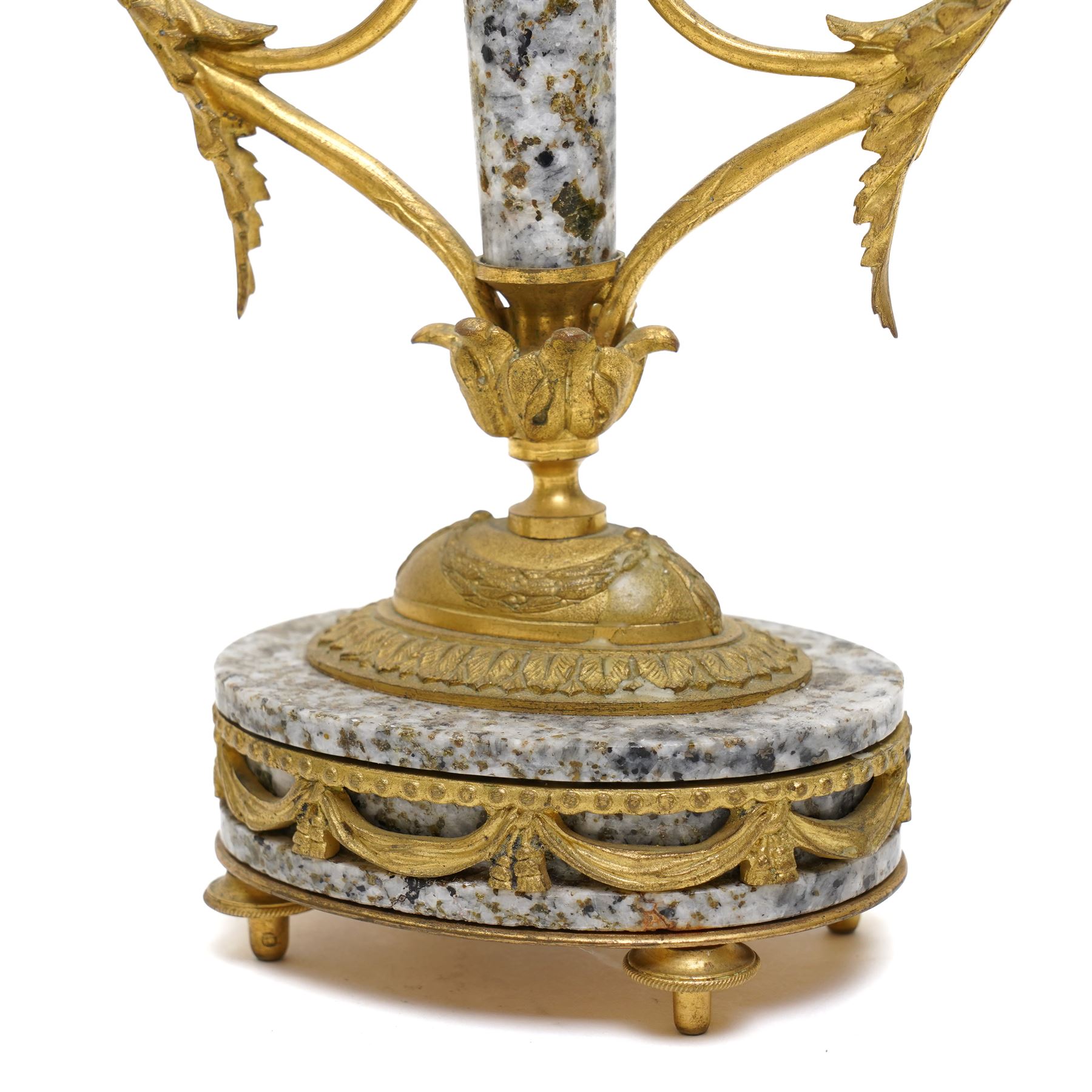 French- early 20th century portico clock garniture, 8-day drum movement decorated with laurel leaves to the glazed bezel and surmounted by a decorative urn with scroll handles, raised by four matching columns on a granite effect oval base with toupee feet, convex enamel dial with gilt pierced hands, Arabic numerals, minute markers and a garland of flowers, twin train Parisian rack striking movement, striking the hours and half hours on a bell. With a sunburst pendulum and key and a matching pair of two-light candelabra.