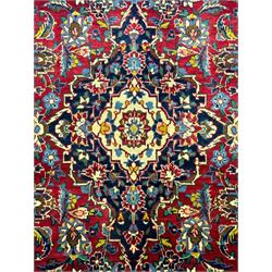 Central Persian Kashan crimson ground rug, central indigo pole medallion surrounded by sparsely placed bouquets interconnected with foliate branches, the guarded border with repeating palmette and Boteh motifs with interwoven scrolling patterns, framed by guard stripes